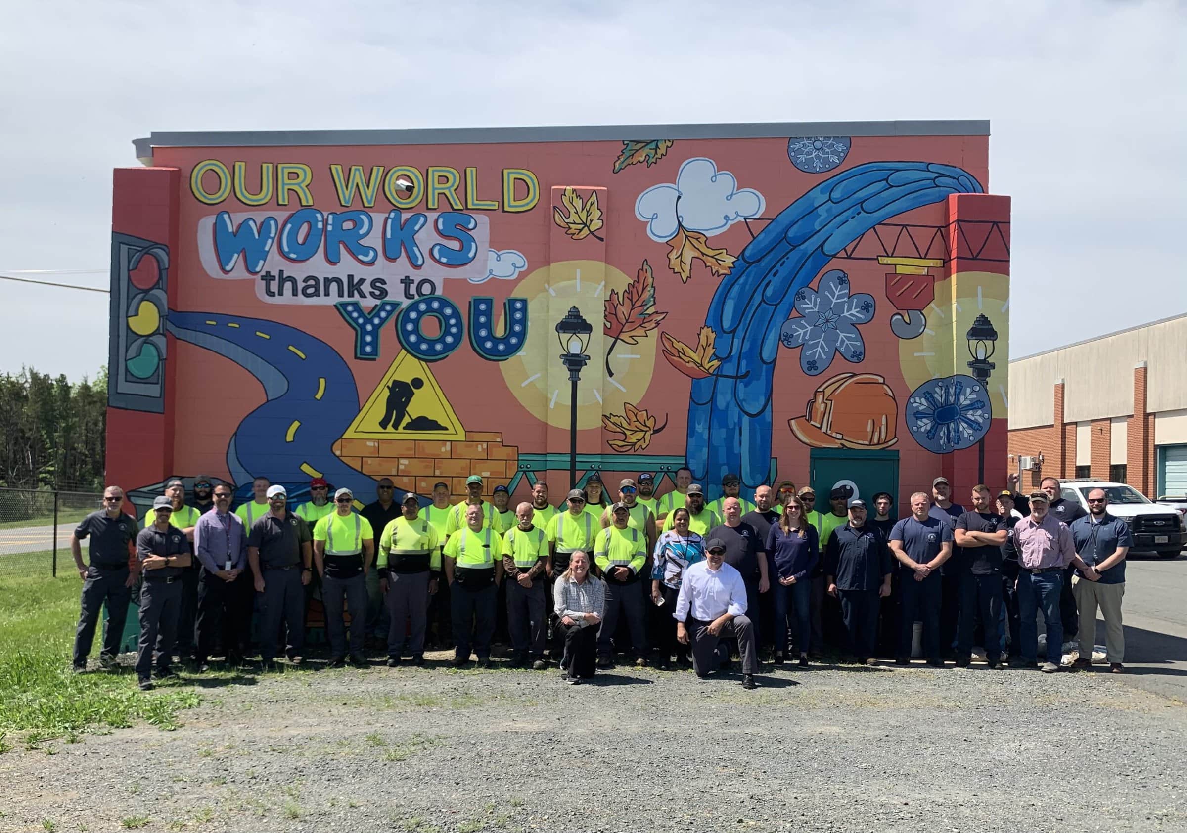 About-APWA-Mission-Statement public works professionals in front of a mural reading, "our world works thanks to you"