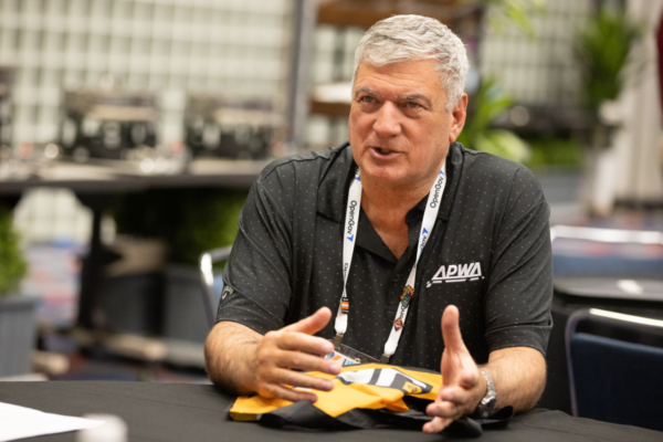 An APWA chapter member in an APWA polo speaks at a conference table.