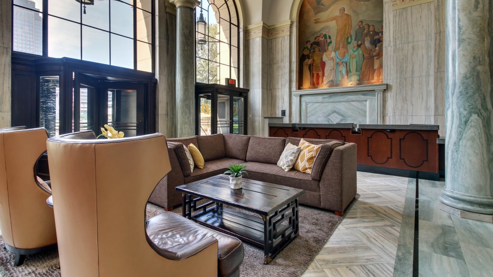 Hotel lobby with chairs and a couch. A painting is seen in the background.