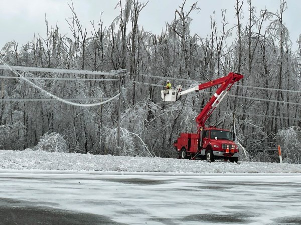 a worker in a bucket truck works on icy power lines