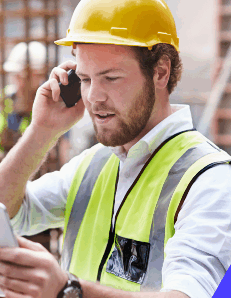 a man wearing a hard hat and safety vest talking on the phone
