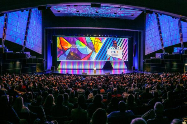 A large crowd of PWX attendees listens as Bertice Berry delivers a keynote, with a colorful display screen at the back of the stage.