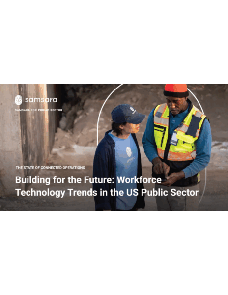 A woman in a baseball cap talks with a man in a yellow vest while the man operates a device.