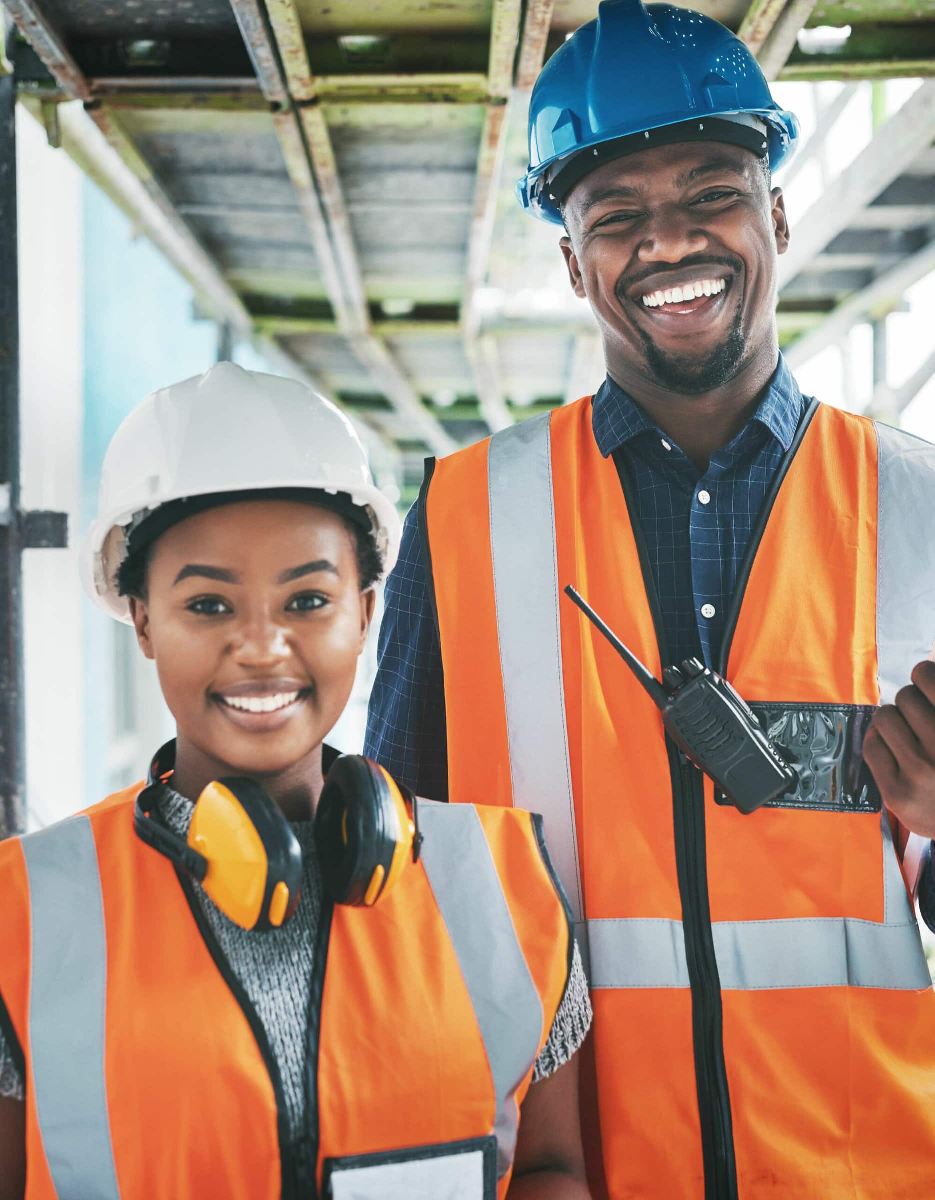 Shutterstock_2190408561 Happy and proud African American engineers at a construction site planning a building together. Portrait of young contractors standing at an apartment to be renovated for a project together