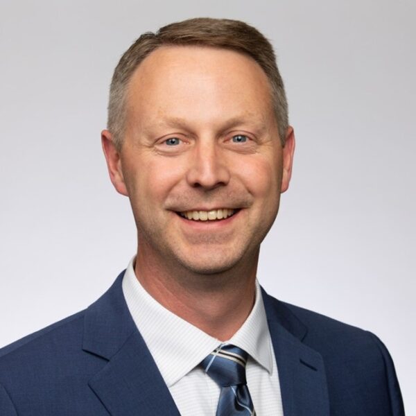Tim Plath smiling for a photo in a suit and tie.
