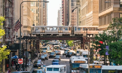 a photo of cars passing under an elevated railway
