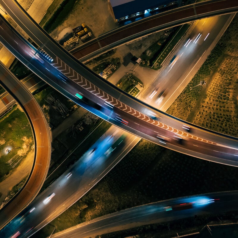 Aerial top view of Highway road junctions. Rush hour traffic on multiple highways in city at night. Transportation and cargo delivery in the industrial city.