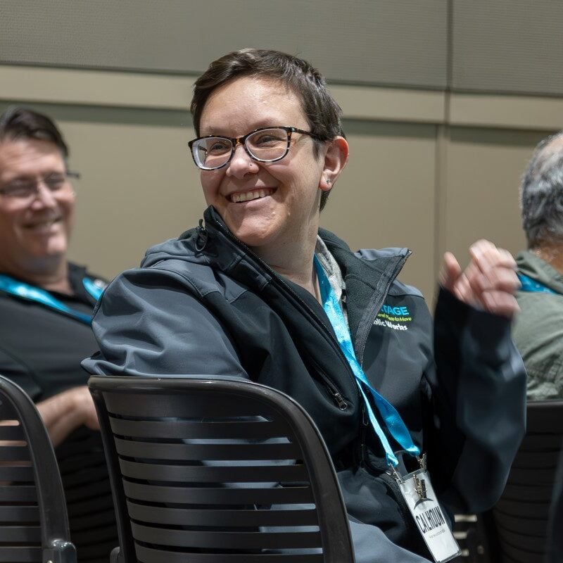 A man wearing glasses and a gray jacket smiles during an APWA education session.