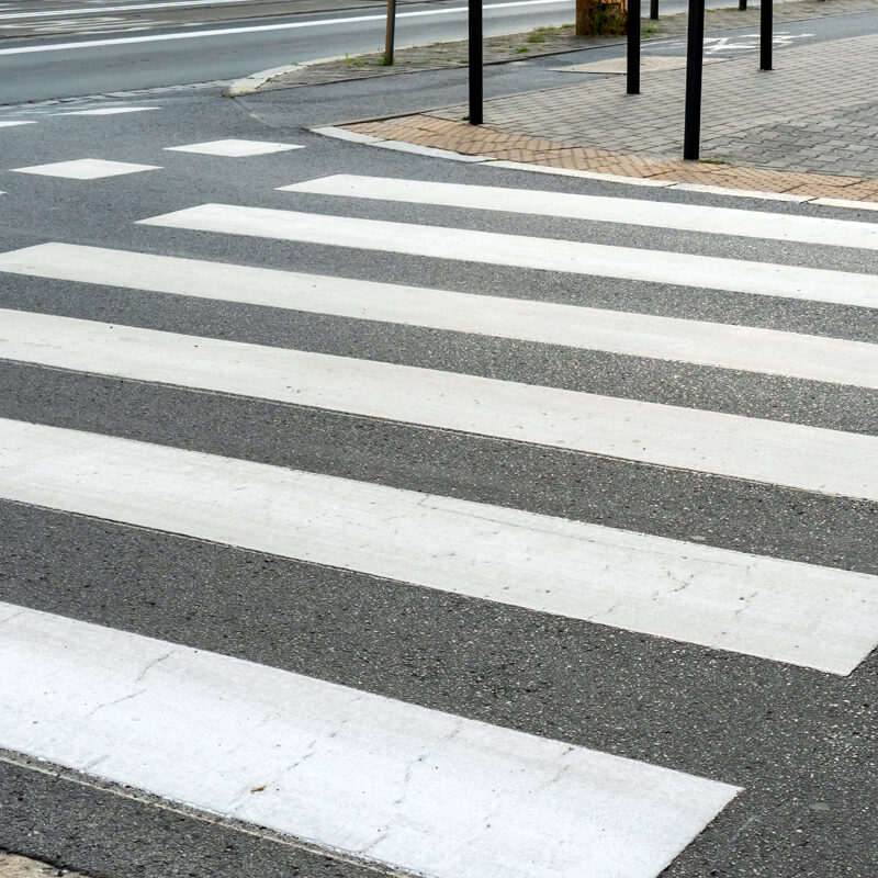 Empty crosswalk on a city street with striped white lines, indicating pedestrian crossing area. Concept of urban infrastructure, pedestrian safety, and road design. High quality photo