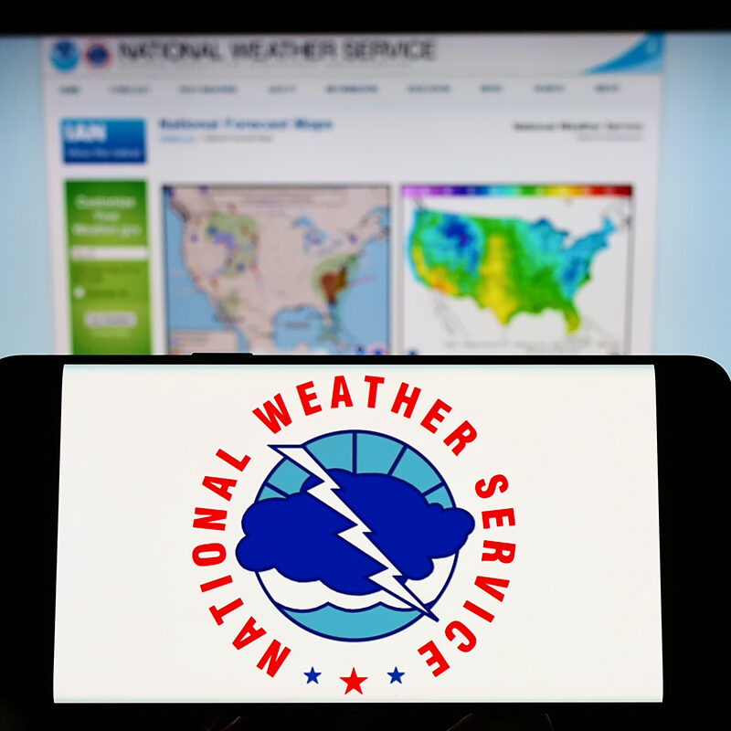 Stuttgart, Germany - 09-30-2022: Person holding mobile phone with logo of American agency National Weather Service (NWS) on screen in front of web page. Focus on phone display. Unmodified photo.