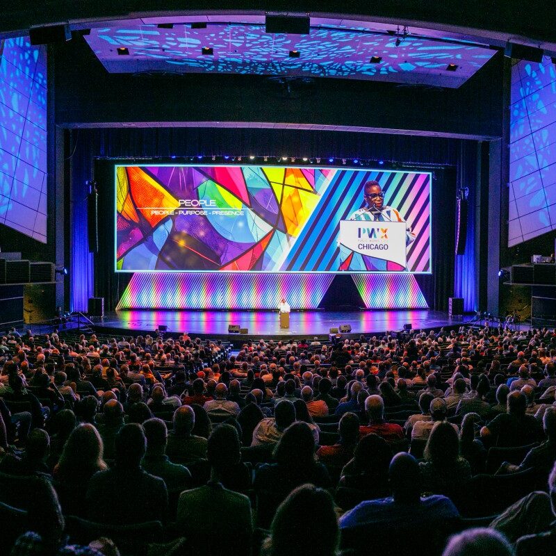 A large crowd of PWX attendees listens as Bertice Berry delivers a keynote, with a colorful display screen at the back of the stage.