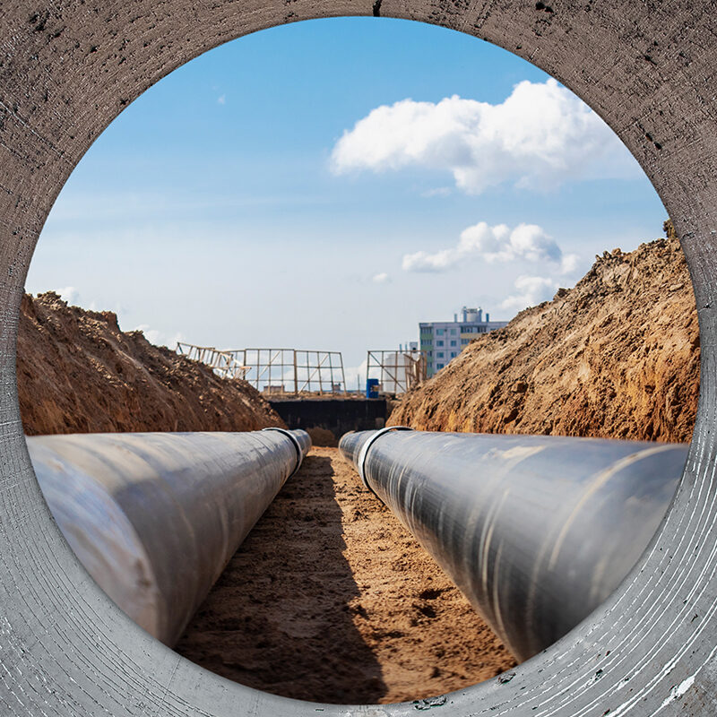 Water pipes for drinking water supply lie on the construction site. View from a large concrete pipe. Preparation for earthworks for laying an underground pipeline. Modern water supply systems