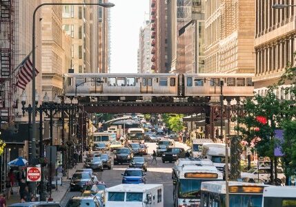 a photo of cars passing under an elevated railway