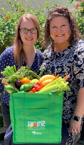 Adah Gorton, Co-manager, Don’t Waste Food SC and another women taking a picture with vegetables and fruits.