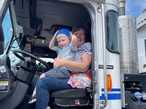 a child and an adult sit in the driver's seat of a truck