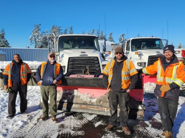 snowplow drivers pose for a photo in front of their trucks